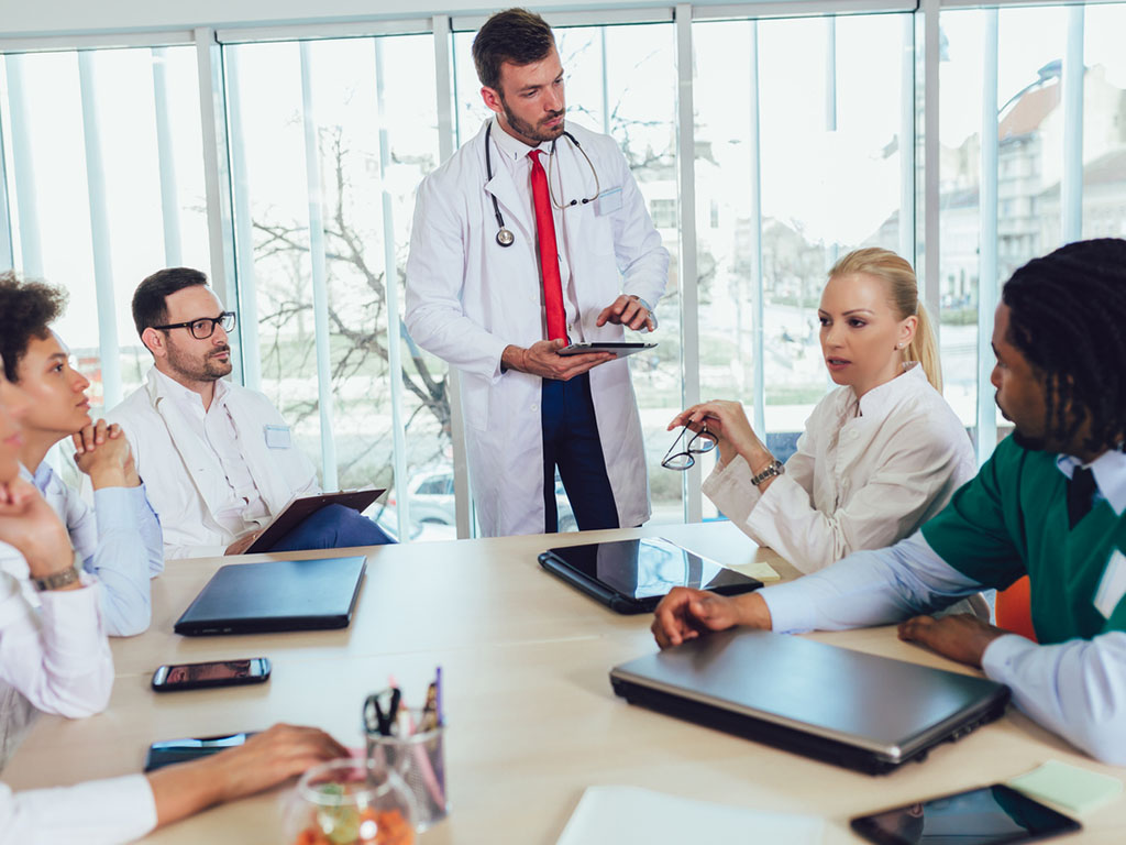 Teambesprechung im Gesundheitswesen mit mehreren Ärzten und Krankenpflegern.