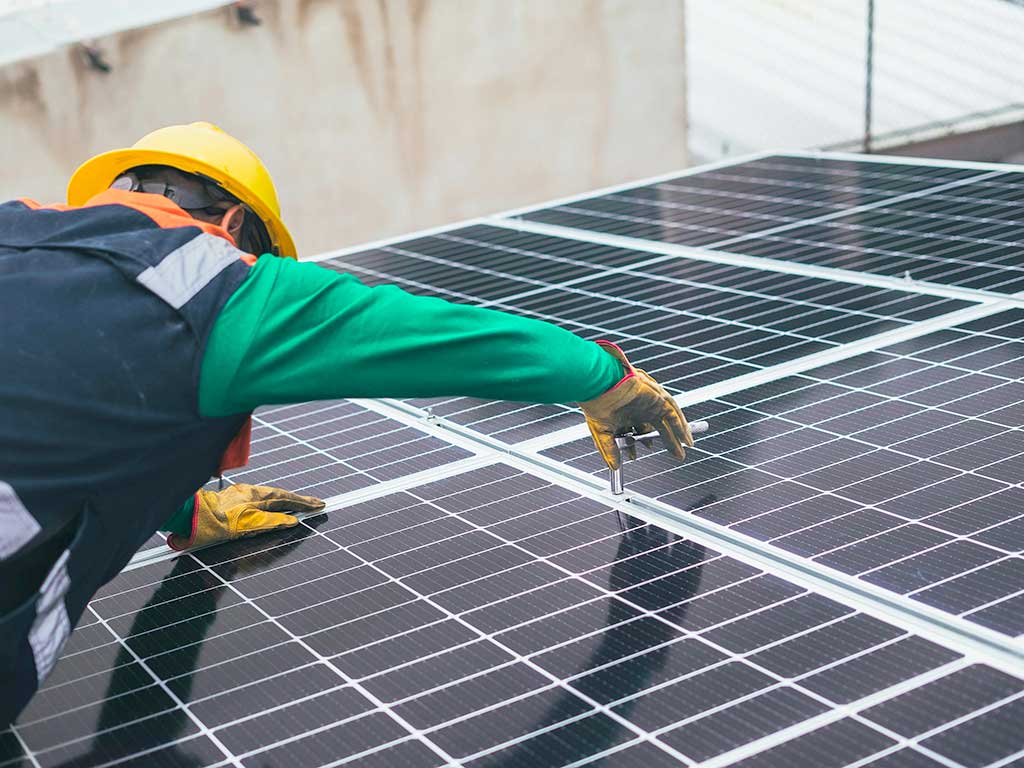 Mann montiert Solar Paneel auf einem Dach