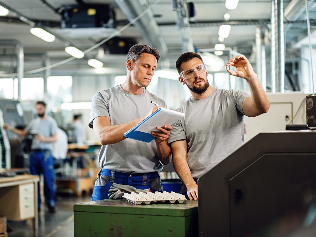 Zwei Mitarbeitende führen in einer Produktionsanlage eine Qualitätskontrolle durch